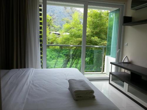 芭东海滩贝克利夫公寓酒店的一间卧室设有一张床和一个大窗户