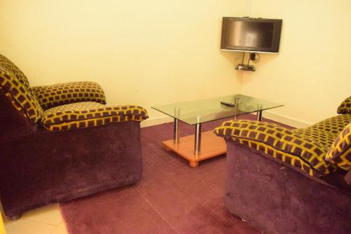 KakamegaBeautiful 1BR with Wi-Fi & secure parking的一间设有两把椅子、一张桌子和一台电视的房间
