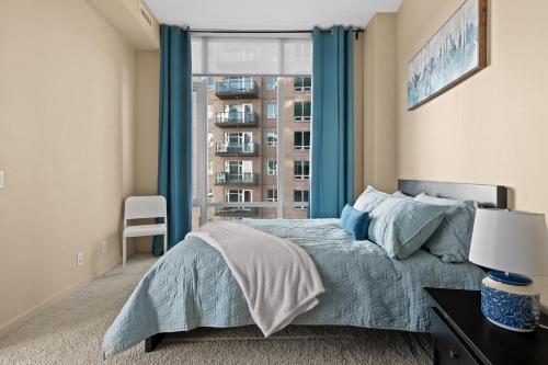 卡尔加里Gorgeous Downtown Calgary Condos by GLOBALSTAY Free Parking的一间卧室配有一张带蓝色窗帘的床和一扇窗户
