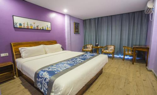 西哈努克Junlan Hotel的一间卧室配有一张紫色墙壁的床和一张桌子