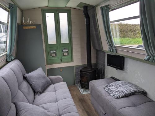 Mini Escape - 2 Berth Narrowboat on the Grand Union, Hertfordshire的带沙发和炉灶的客厅