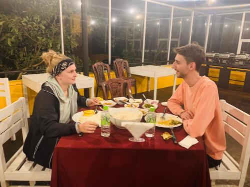 明内里耶Sethway Village的坐在餐桌旁吃食物的男人和女人