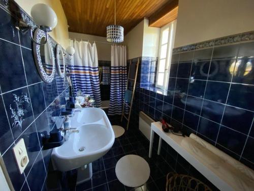 ValeillesDomaine des pruniers的蓝色瓷砖浴室设有水槽和镜子