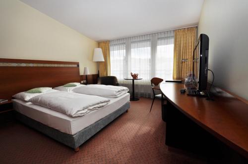 雷根斯堡雷根斯堡汉萨公寓酒店的酒店客房配有一张床和一张书桌及一台电视