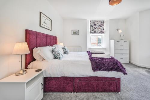 托基The Falstone Apartment的一间卧室配有一张大床和紫色床头板
