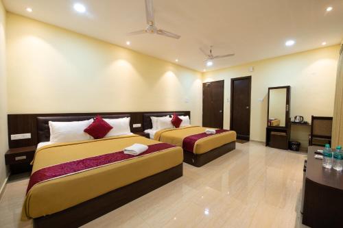 钦奈Sugam Resort & Convention Centre的酒店客房设有两张床和一张桌子。