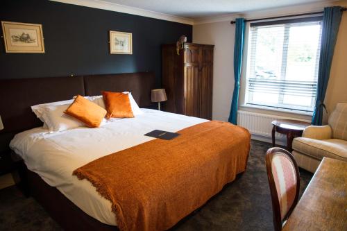 切尔滕纳姆The Charlton Boutique Hotel的一间卧室配有一张带橙色毯子的床
