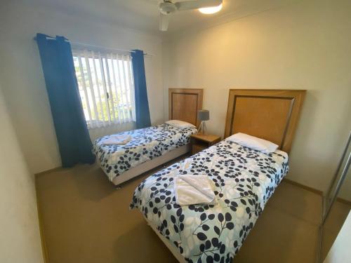 朱里恩湾Unit 46 Seafront Estate的一间卧室设有两张床,窗户配有蓝色窗帘