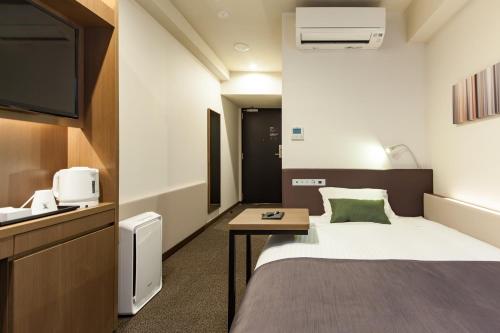 尼崎市阪神神崎前根Y‘s酒店的一间酒店客房,配有一张床和一台电视