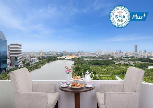 曼谷素坤逸10中心点酒店的阳台配有两把椅子和一张桌子,享有河景。