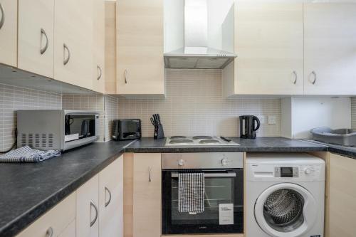 伦敦APlaceToStay Central London Apartment, Zone 1 WAT的厨房配有白色橱柜和一台洗衣机
