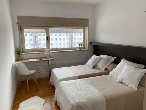 卢戈Hospedería San Froilan的一间卧室设有两张床、一张桌子和一个窗口。