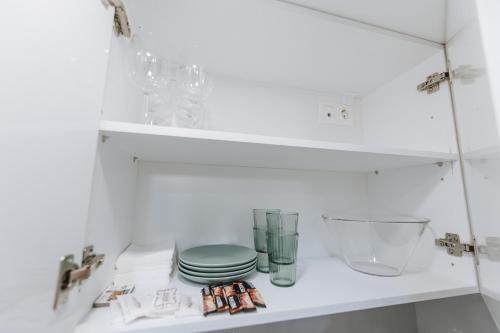雅典Your Cozy Sapphire Apartment的架子上装有板子和玻璃杯的白色橱柜