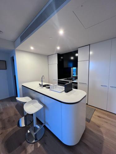悉尼KozyGuru Bondi Junction Lovely 1 Bedroom Walk to Station NBD241的厨房配有白色橱柜、水槽和凳子