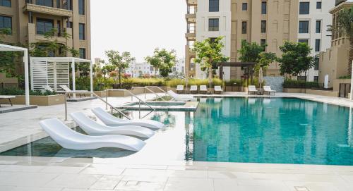 迪拜Madinat Jumeirah Living的一座带白色椅子的游泳池以及建筑