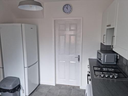 埃尔斯米尔港3 bedroom house-Ellesmere Port的厨房设有白色的门和墙上的时钟
