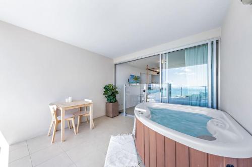 埃尔利海滩Three A Airlie Seaviews, Pool, Private Spa的带浴缸的浴室,配有桌子和窗户