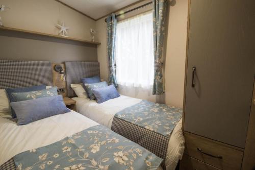 威利Lovely 6 Berth Caravan With Wi-fi At Weeley Bridge In Essex Ref 69015r的一间卧室设有两张床和窗户。