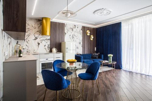 卡托维兹Luksusowy Apartament Przy Filharmonii的厨房以及带蓝色椅子和桌子的客厅。