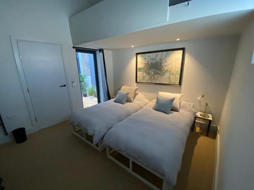 特威克纳姆May Road, stylish townhouse的一间卧室设有两张带白色床单的床和窗户。