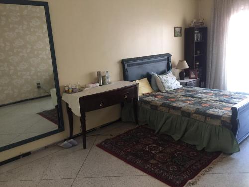 卡萨布兰卡Room in Guest room - Property located in a quiet area close to the train station and town的一间卧室配有一张床、一张书桌和一面镜子