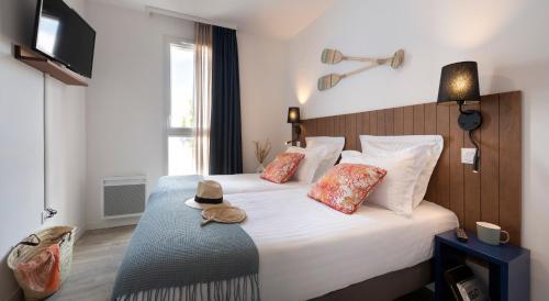 莱萨布勒-多洛讷Pierre & Vacances Premium Les Villas d'Olonne的酒店客房,配有带帽子的床