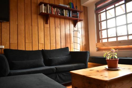 圣卡洛斯-德巴里洛切Cinerama Hostel的客厅配有黑色沙发和咖啡桌