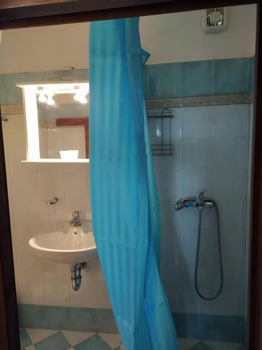 古卡斯特隆Kouros House - Zen Philosophy的带淋浴、水槽和蓝色窗帘的浴室