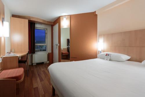 克莱蒙费朗克莱蒙费朗苏德哈贝特宜必思酒店的酒店客房设有一张大床和一张书桌。