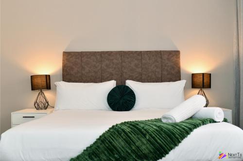 比勒陀利亚Next To Apartment Hotel的一间卧室配有一张带两盏灯的大型白色床。
