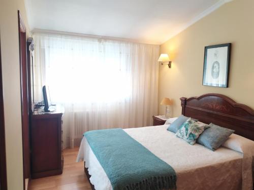 艾利亚德亚罗萨Piso Avenida Castelao XXL的一间卧室配有一张带蓝色枕头的床和一扇窗户。