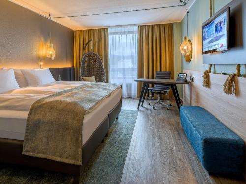 上乌瑟尔elaya hotel frankfurt oberursel的酒店客房设有一张大床和一张书桌。