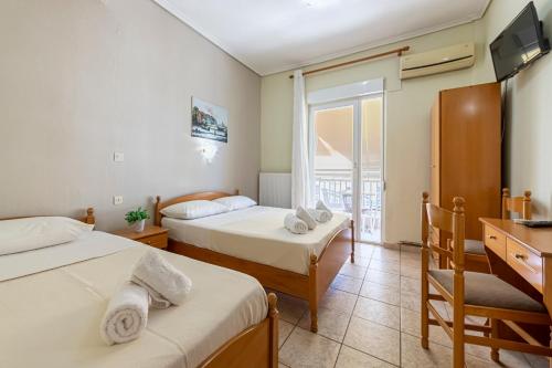 帕拉利亚卡泰里尼斯Lucia Hotel Paralia的一间卧室设有两张床、一张桌子和一个窗口。
