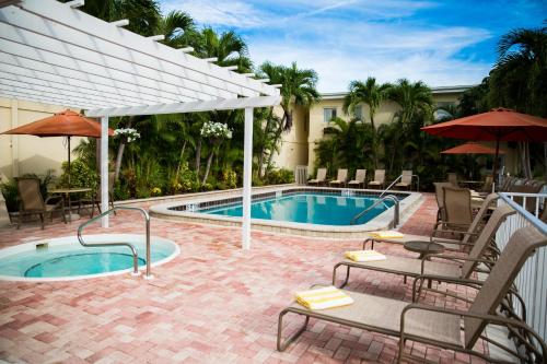 威尼斯Inn at the Beach-Venice FLORIDA的游泳池配有椅子、桌子和遮阳伞