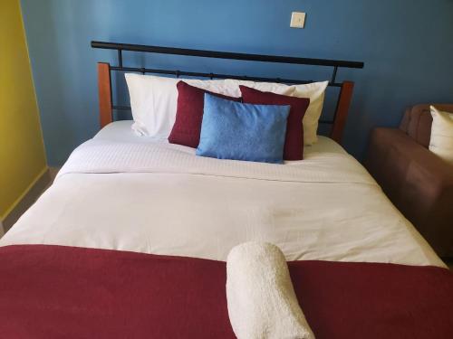 内罗毕MAMU'S RESIDENCE near JKIA的一张大床,上面有红色和蓝色的枕头