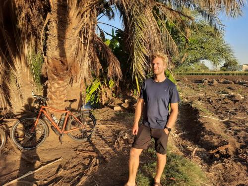 明亚Village Room in the Countryside的站在自行车旁的棕榈树旁的男人