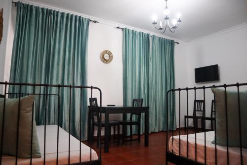 卡莫纳Apartamentos Turisticos Casa Cantillo的一间卧室配有绿色窗帘和桌椅