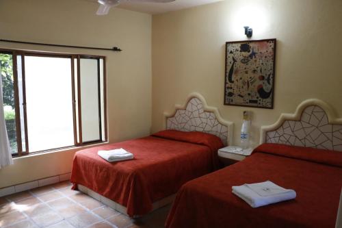 Apazapan扎尔温泉酒店的客房设有两张带红色床单的床和窗户。