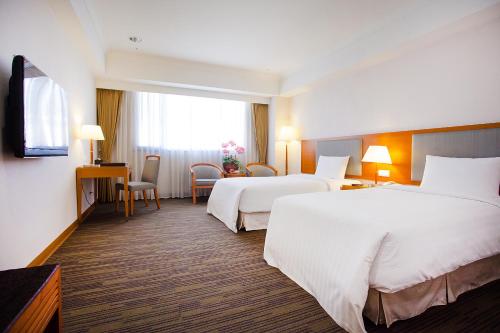 台中市台中富信大飯店的酒店客房设有两张床和电视。