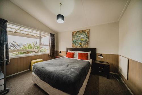 特卡波湖Lakes Edge Holiday Park的一间卧室配有带橙色枕头的床和窗户。