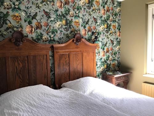 奥门Rembrandthuis的一间卧室配有一张带花卉壁纸的床