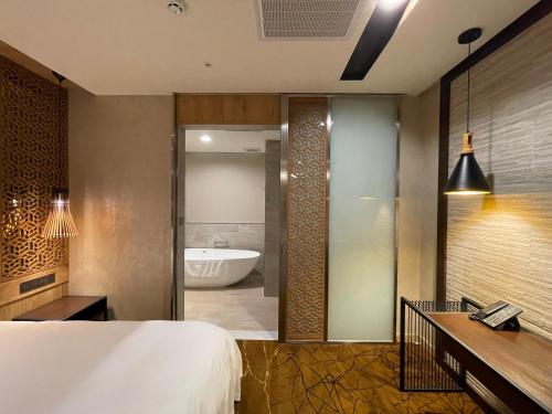 台南夏都城旅安平馆的一间卧室配有一张床,浴室设有浴缸