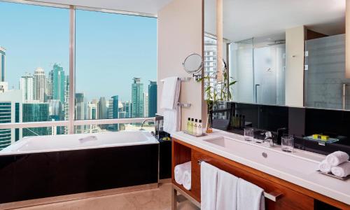 多哈InterContinental Doha The City, an IHG Hotel的带浴缸的浴室和大窗户