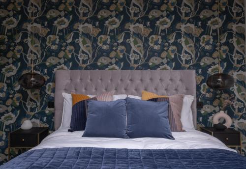 纳尔斯伯勒Honeysuckle Lodge的一间卧室配有一张蓝色床单和花卉壁纸的床