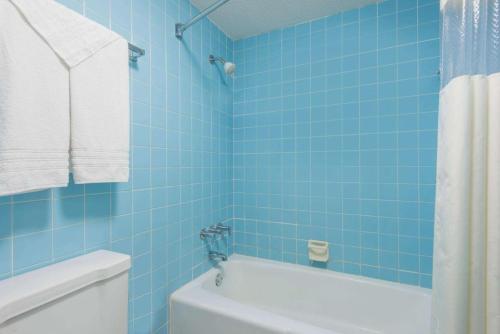 黑泽尔伍德Haven Inn & Suites St Louis Hazelwood - Airport North的蓝色瓷砖浴室设有浴缸和卫生间