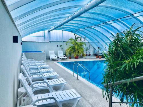萨帕雷瓦巴尼亚ENIS Hotel с минерален басейн的一个带白色躺椅和蓝色天花板的游泳池