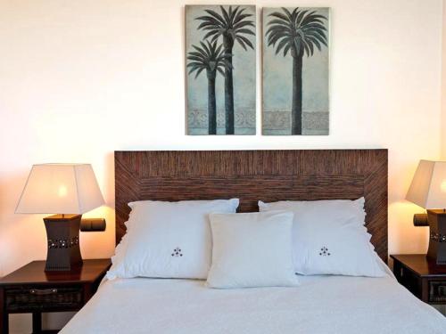 马斯帕洛马斯Holiday Home Villa Gema, spacious, scenic, Wlan ,AC的一间卧室配有一张带两盏灯和两棵棕榈树的床。