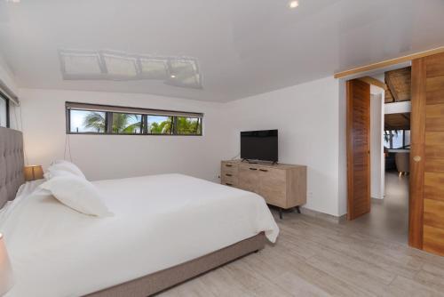 普纳奥亚Jolie Maison Vue Ocean et Moorea的一间白色卧室,配有床和电视