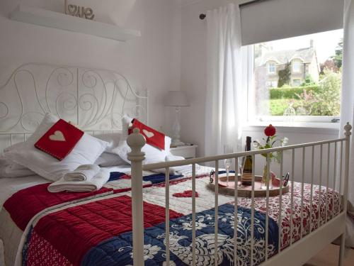 克里夫Tree Tops的一张白色的床,上面有红蓝色的毯子和一个窗口