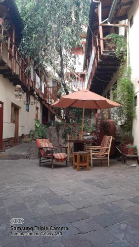 库斯科Hostal sambleño cusco Piero suite的庭院配有桌椅和遮阳伞。